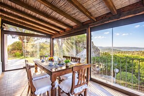 Comedor con mesa lista para cuatro, con vista a un paisaje pintoresco.