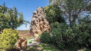 A natural rock formation surrounded by greenery and a pathway.