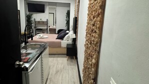 Une cuisine moderne dotée d’une cuisinière intégrée, d’un petit coin repas et d’une chambre avec un lit et un téléviseur.