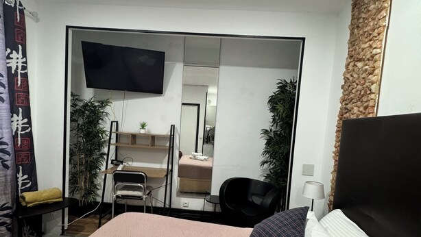 Une chambre d’hôtel avec un lit, un bureau, une chaise, une télévision et un miroir.