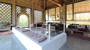 Een ruime woonkamer met hoge plafonds, grote ramen en een centraal ziteiland met kussens.