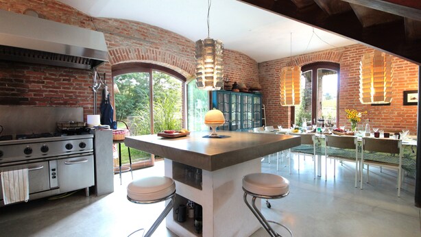 Een keuken met een groot schiereiland, barkrukken, een fornuis en uitzicht op de omgeving.