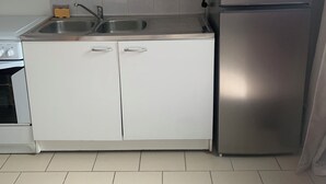A compact kitchen with white cabinets, a stainless steel refrigerator, a microwave, and a sink. - Apartment in the countryside 30mn from the 24h of Le Mans (Saint-Georges-du-Rosay)