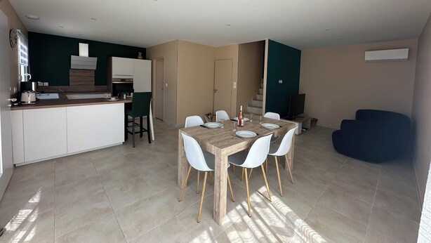 A modern kitchen with a dining area, a TV, and a staircase leading to another level. - Bright, quiet house in Redessan (Redessan)