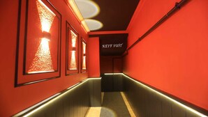 Um corredor com paredes vermelhas, iluminação emoldurada e uma placa com a inscrição KEYF SUIT.