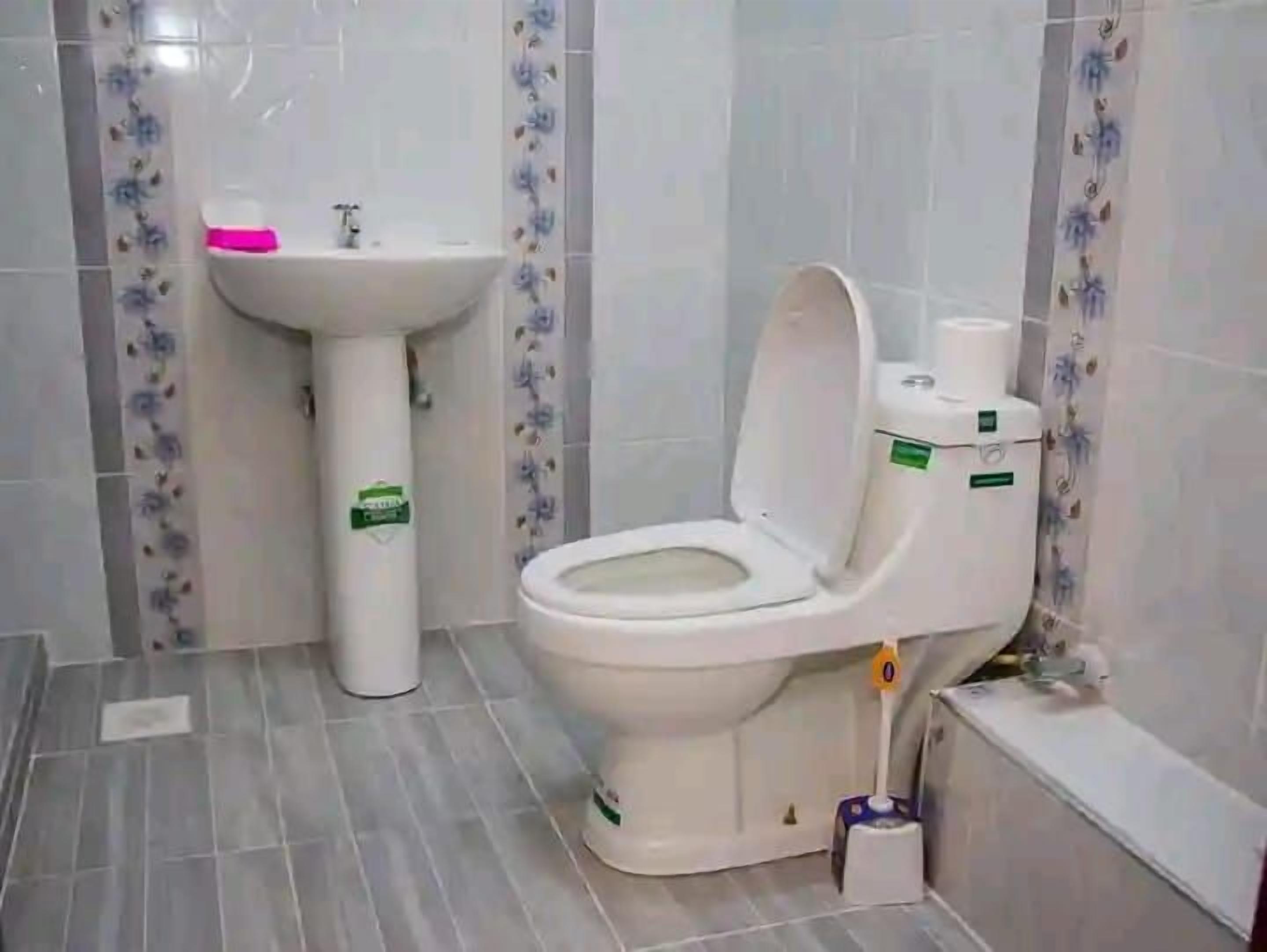 Un baño con inodoro, lavamanos y paredes con azulejos.