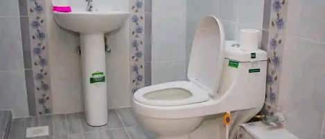 Une salle de bain avec des toilettes, un lavabo et des murs carrelés.