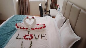 A bed with a heart-shaped decoration made of rose petals and a swan design, with the word "LOVE" spelled out in flowers.