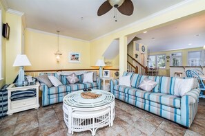Ein Wohnzimmer mit zwei Sofas, einem runden Couchtisch und einem Deckenventilator.