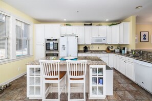 A kitchen with white cabinets, a granite countertop, and a built-in oven. - Sunset Island 43 Sunset Island Drive (Ocean City)