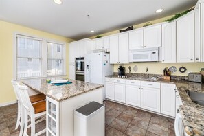 A kitchen with white cabinets, a granite countertop, a stainless steel sink, and a microwave. - Sunset Island 43 Sunset Island Drive (Ocean City)