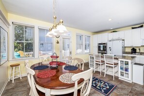 A dining area with a wooden table, white chairs, and a chandelier.