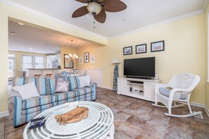 A living room with a sofa, a television, a white rocking chair, and a ceiling fan. - Sunset Island 43 Sunset Island Drive (Ocean City)