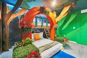 Un dormitorio con cama, una escalera y una puerta verde.