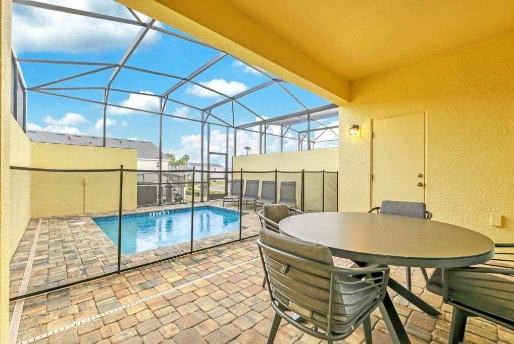 Un espacio exterior cubierto con piscina, una mesa y sillas.