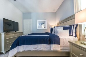 Un dormitorio con una cama, televisión, una puerta y un cuadro en la pared.