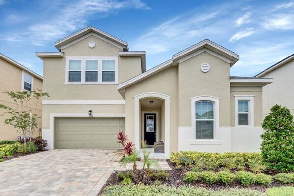 A two-story house with a garage, a front entrance, and a landscaped front yard. - 1513nassau 5 Bedroom Villa (Kissimmee)