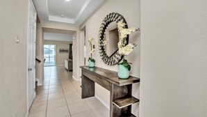A hallway with a wooden console table, a large mirror, and two potted plants. - 1513nassau 5 Bedroom Villa (Kissimmee)