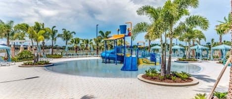 A pool area with a blue play structure, palm trees, and lounge chairs.