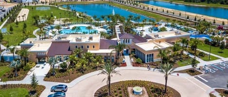 Vista aérea de un resort con piscina, varias edificaciones y un estacionamiento.