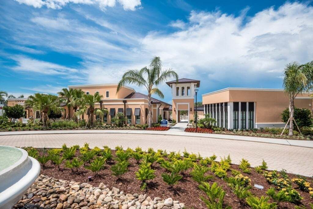 A hotel with a central courtyard, palm trees, and a clear sky.