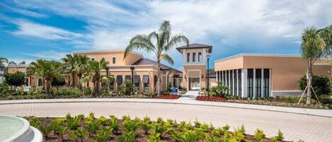 A hotel with a central courtyard, palm trees, and a clear sky.
