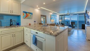 A spacious kitchen with a large island, white cabinetry, and blue tiles.