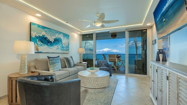 A modern living room with a sofa, coffee table, and a view of the ocean through large sliding doors.