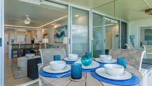 A dining area with a round table set for four, featuring white plates, blue glassware, and a decorative blue glass bowl.
