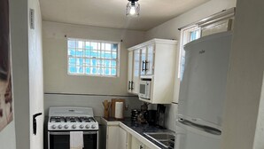 A compact kitchen with white cabinets, a stove, a microwave, and a refrigerator.