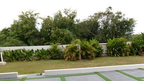 A landscaped garden with a paved area featuring geometric patterns and a white wall in the background.