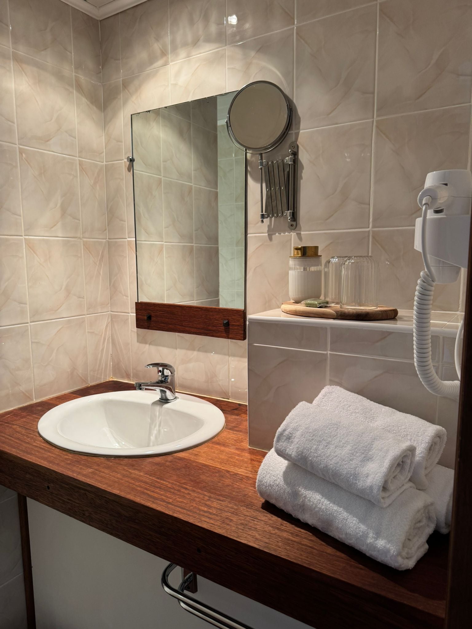 A bathroom with a sink, mirror, towel rack, and hairdryer.