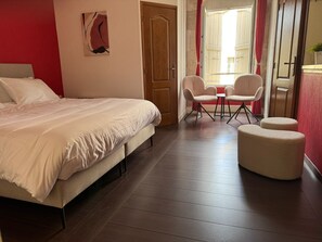 A bedroom with a bed, a chair, a small table, and a window with curtains. - Le Cozy (Saint-Jean-Poutge)