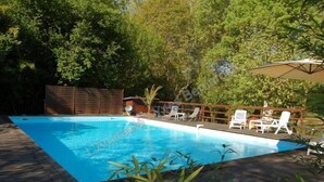 A rectangular swimming pool with a wooden deck surrounding it.