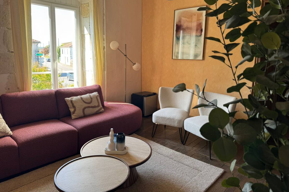 Una sala de estar con un sofá rojo, un sillón blanco y una mesa de centro redonda.