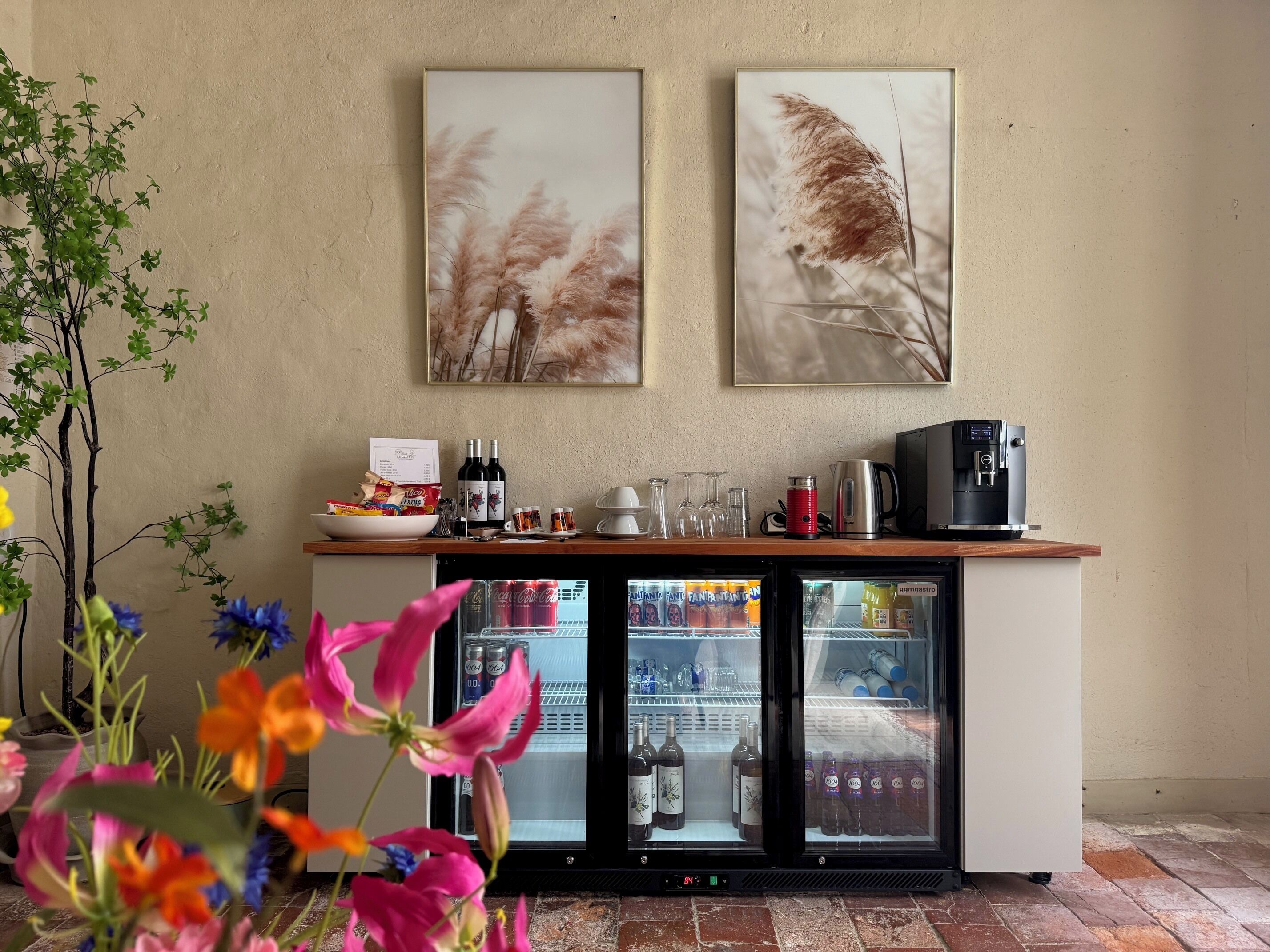 A minibar area with a refrigerator, wine bottles, and a coffee machine.