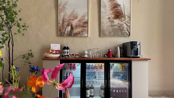 A minibar area with a refrigerator, wine bottles, and a coffee machine.