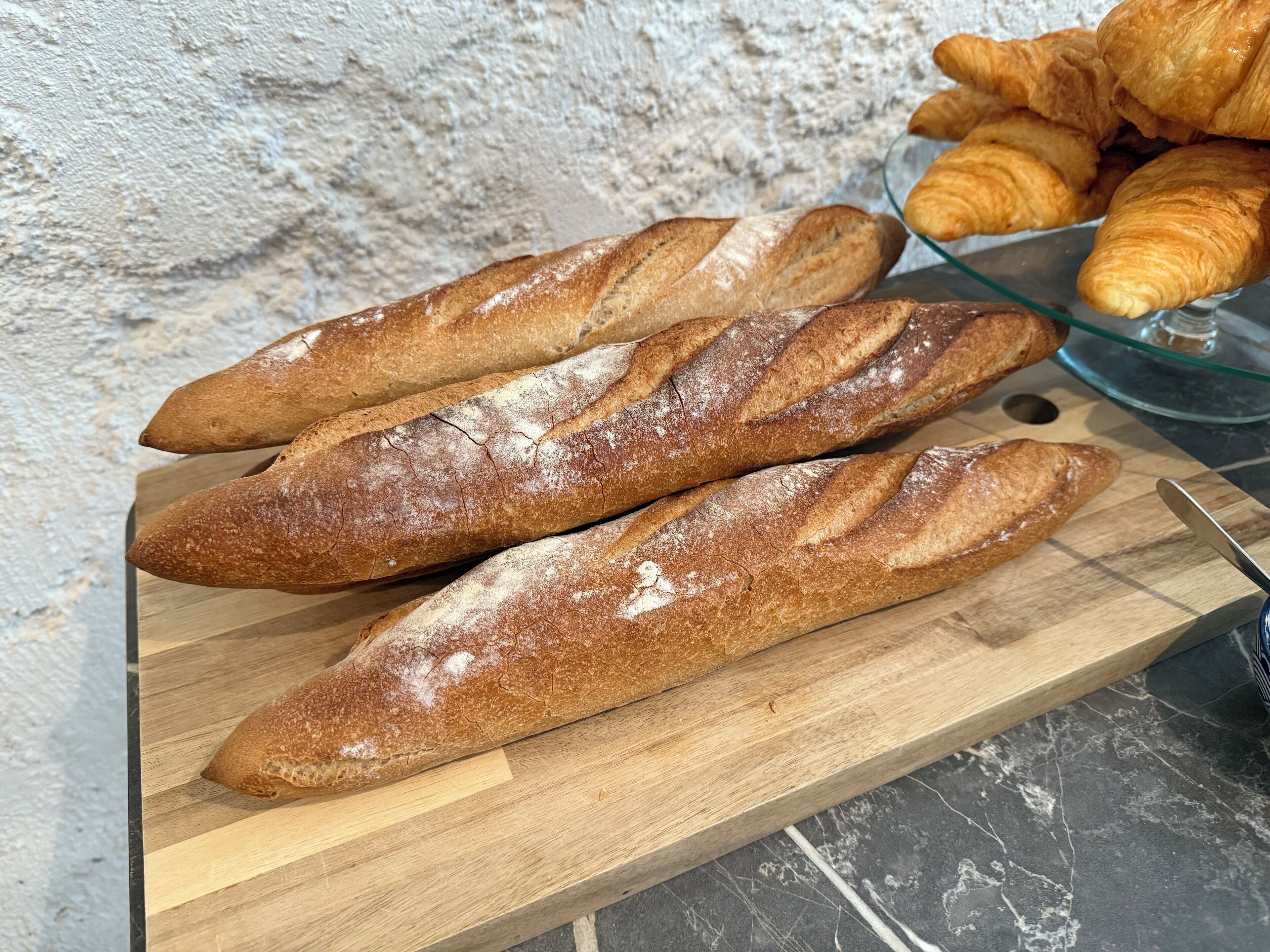 Three baguettes on a wooden cutting board.