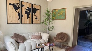 A living room with a sofa, a small table, and a chair. There are three world maps on the wall.