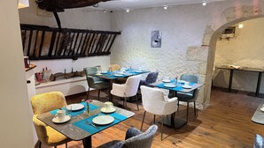 A dining area with wooden floors, rustic decor, and tables set for four.
