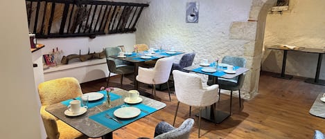 A dining area with wooden floors, rustic decor, and tables set for four.