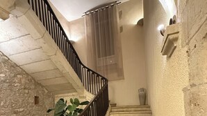 A curved staircase with a black railing, stone walls, and a small window.