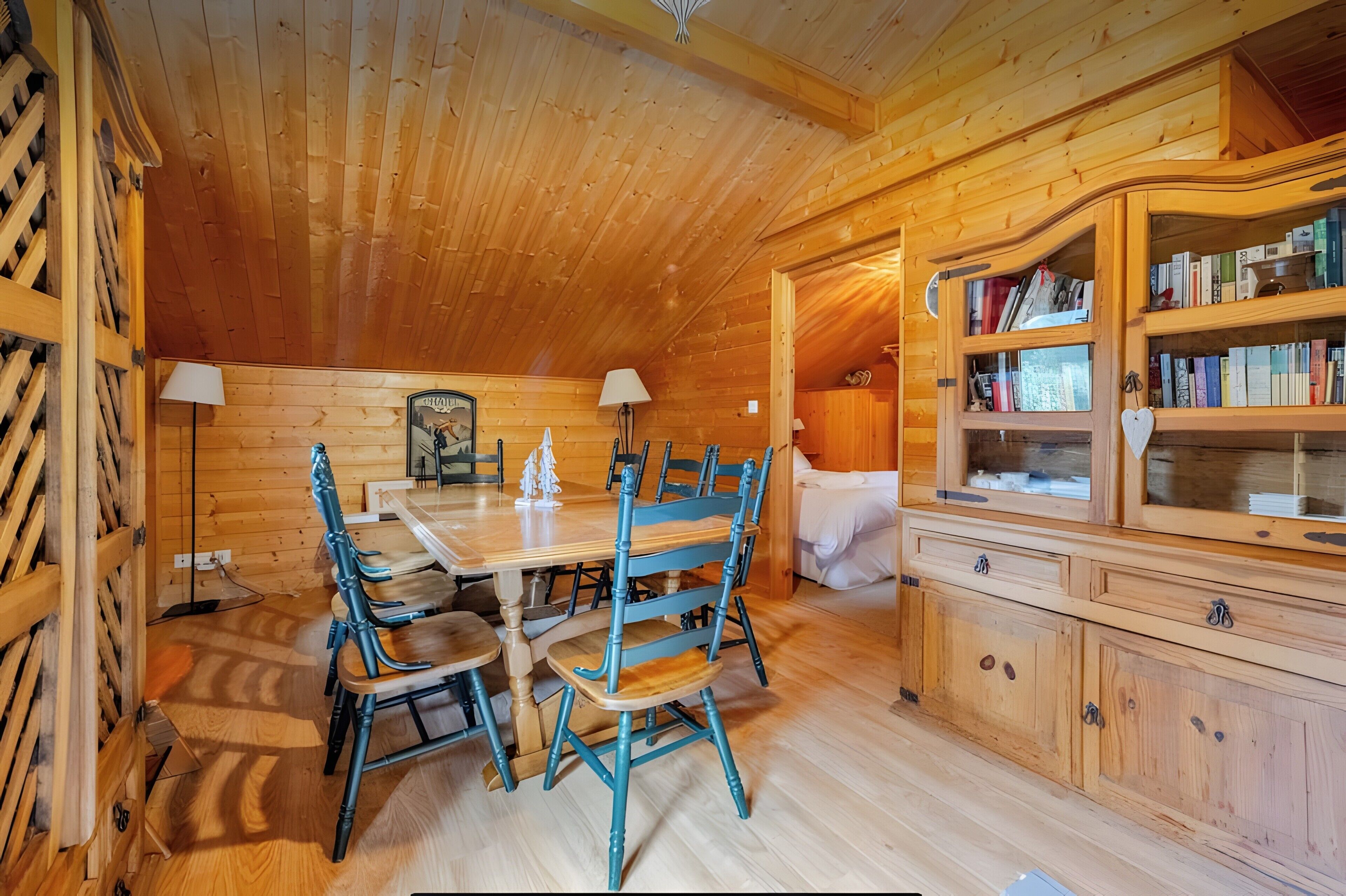 Un intérieur en bois comprenant une table à manger, des chaises, une bibliothèque et une lampe.