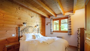 Ein Schlafzimmer mit Holzwänden, einem Bett, einem Schminktisch und einem Fenster mit Vorhängen.