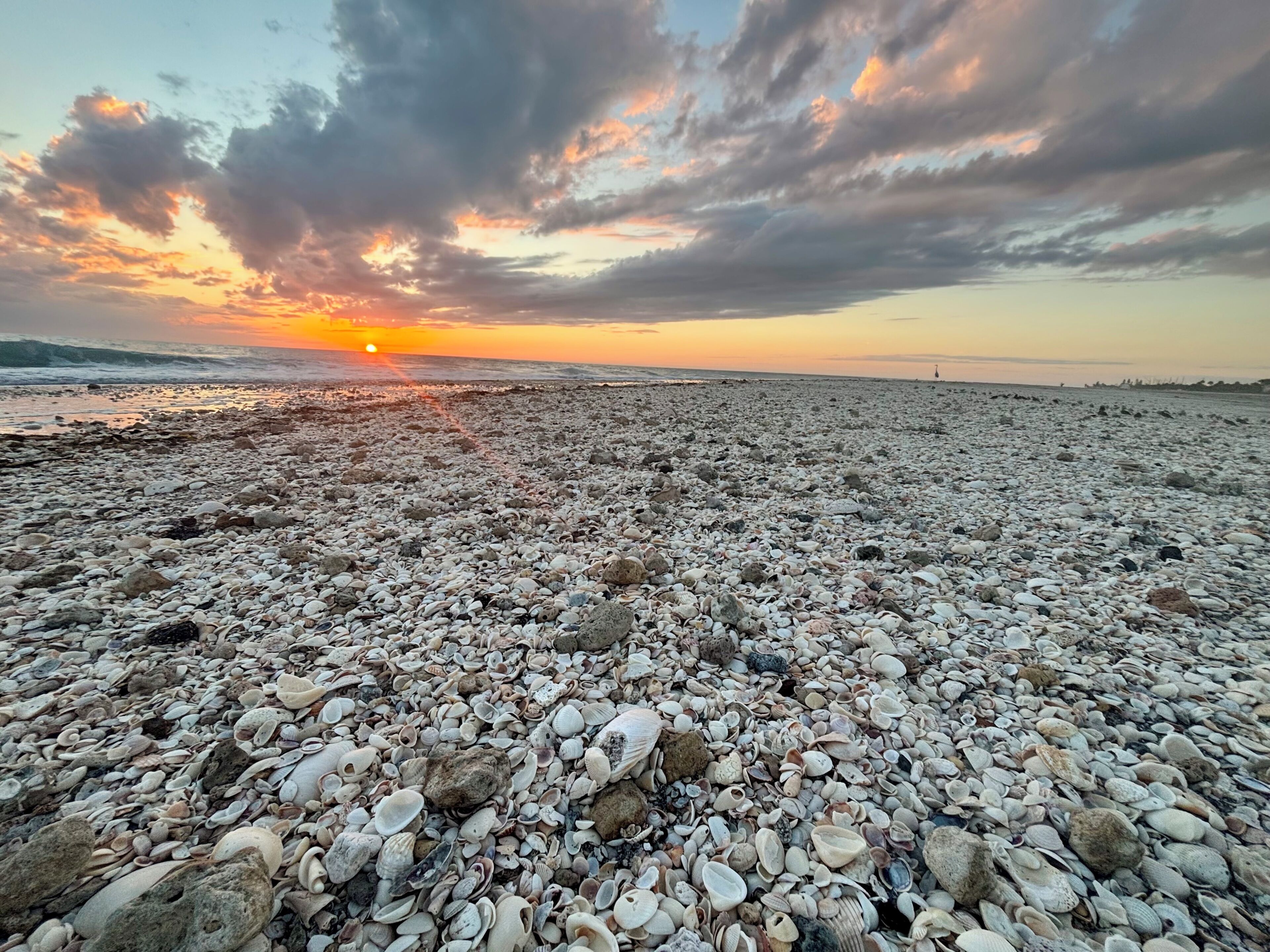 A pebble beach with a sunset in the background.