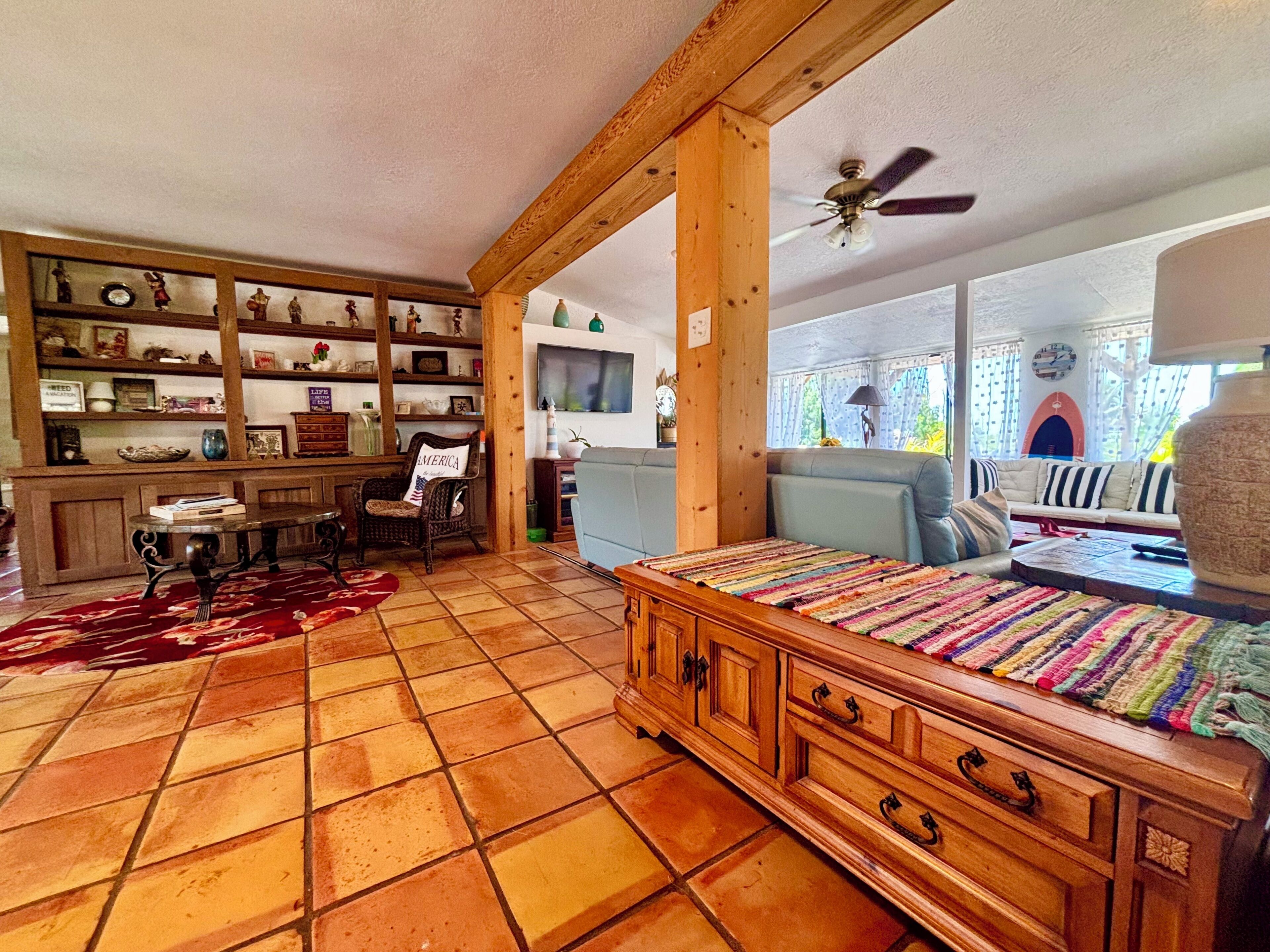 A cozy living room with a wooden cabinet, a sofa, a colorful rug, and a ceiling fan.