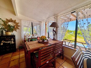A sunlit room with a wooden table, chairs, a lamp, and a view of greenery outside. - Boater's Dream & Beach Haven. Direct Gulf Access! No Bridges. Englewood Getaway. (Englewood)
