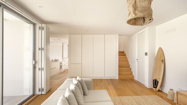 A modern living room with a sofa, a staircase, and a surfboard. - Ericeira Modern Bright With Pool by Homing (Mafra)