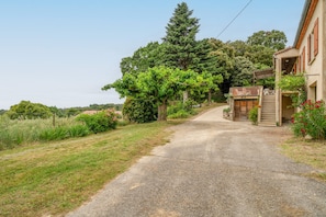 A rural road leading to a house with a covered porch and a staircase.