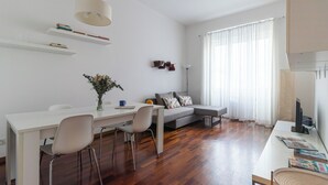 A modern living room with a dining area, a sofa, a coffee table, and a TV. - Italianway Easy - Papiniano 38 (Milan)